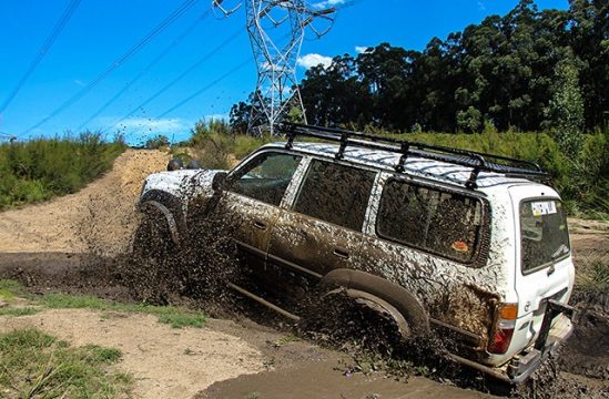 LandCruiser 80 Series wagon playing in a wet bog on a bush track.