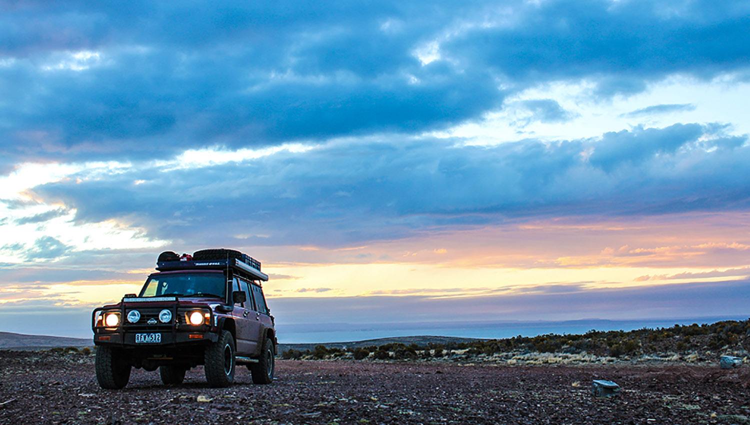 Nissan Patrol with Tradesman Oval Alloy roof rack in Argentina on a rocky plain with sunset in background.